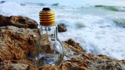 Close-up of bottle on beach
