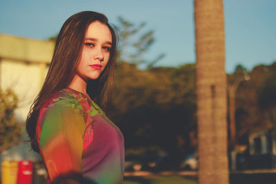 Portrait of beautiful young woman standing against sky