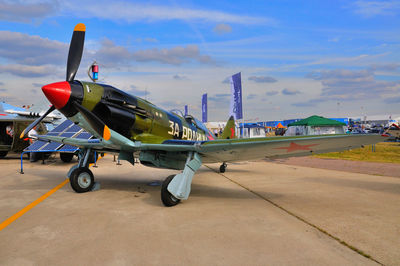 Airplane on airport runway against sky