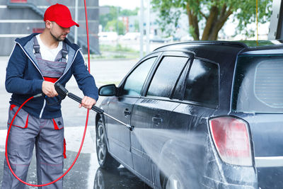 Side view of man standing in car