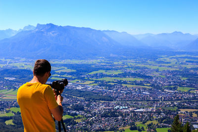 Rear view of man photographing cityscape against sky