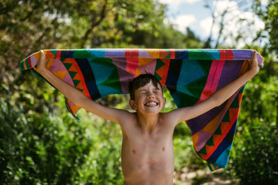 Young boy with towel at beach on summer vacation with a big smile