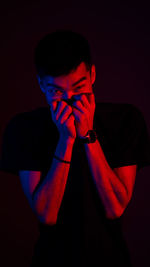 Portrait of young man standing against black background