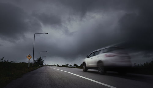 Cars on road against cloudy sky