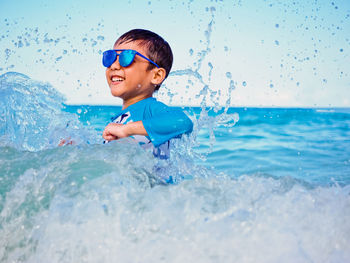 Full length of boy splashing water in sea