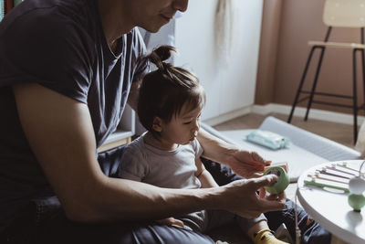 Midsection of father playing with male toddler in living room