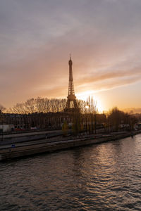 River by building against sky during sunset