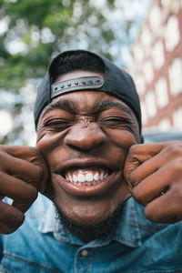 Close-up of young man pulling cheeks outdoors