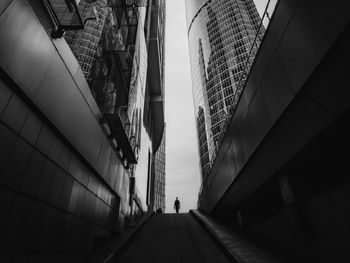 Low angle view of people walking on footpath amidst buildings