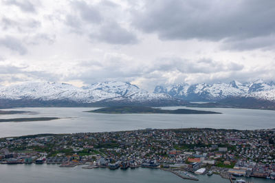 Aerial view of townscape by snowcapped mountains against sky