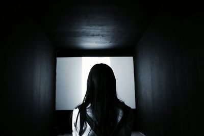 Rear view of woman looking at projection screen in darkroom