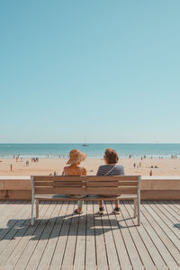 Rear view of people sitting on beach