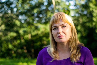 Portrait of young woman standing against trees