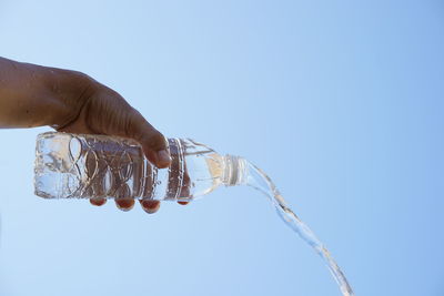 Close-up of hand holding glass against clear sky