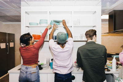 Rear view of multiracial male and female students in kitchen at college dorm