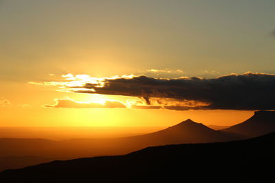 Scenic view of silhouette mountains against romantic sky at sunset