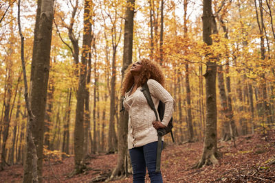 Woman with backpack standing in autumn forest