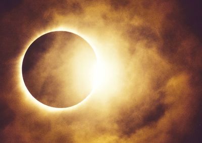 Low angle view of sun shining through moon