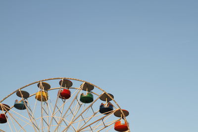 Low angle view of ferris wheel against clear blue sky