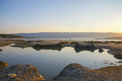 Scenic view of lake against clear sky during sunset