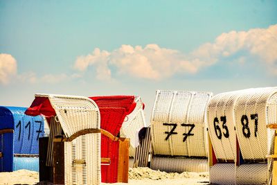 Hooded chairs on beach against sky