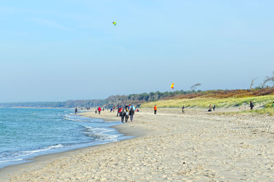 Scenic view of beach with people against sky