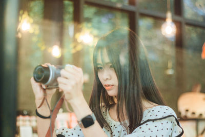 Portrait of young woman photographing through camera