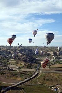 Hot air balloons flying over landscape against sky