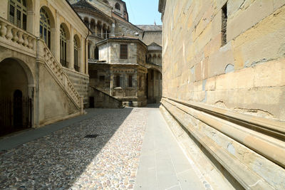 Walkway amidst buildings against sky