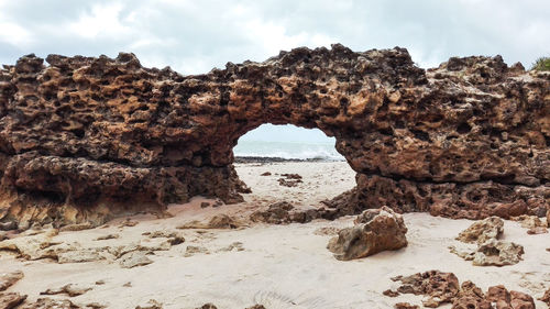 Rock formation on beach against sky