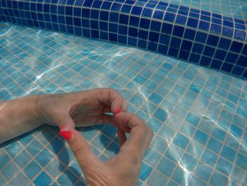 Cropped hand of woman making heart shape in swimming pool