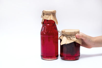 Hand holding glass of jar against white background