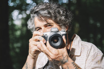 Portrait of a man taking a photo of the viewer with a vintage camera person