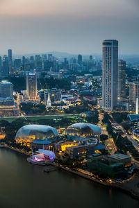 High angle view of illuminated buildings by river against sky