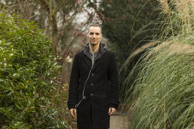 Young man standing by tree