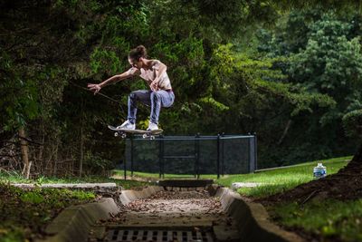 Full length of man jumping with skateboard at park
