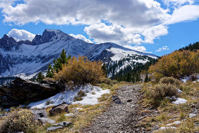 Scenic view of stream by mountains against sky during winter