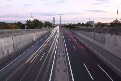 Light trails on road in city against sky