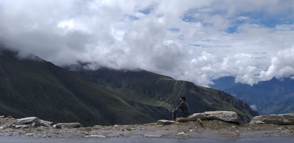 Man looking at view against mountains and cloudy sky