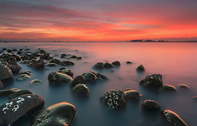 Scenic view of rocks in sea against sky at sunset
