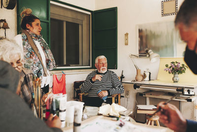 Thoughtful senior man sitting with artists at home