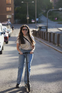 Happy young woman riding push scooter