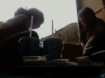 Close-up of people sitting on wall