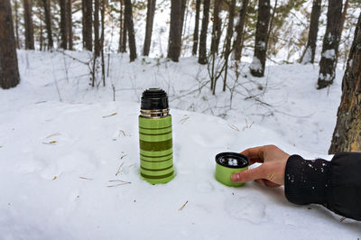 Person holding bottle on snow covered field