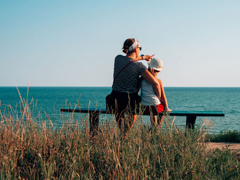 Happy motherand daughter sitting on bench marine landscape mom and child having fun walking together