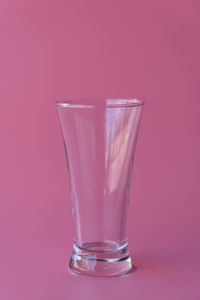 Close-up of glass against pink background