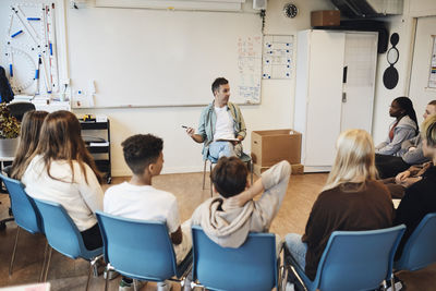 Mental health professional discussing with male and female students in group therapy at school