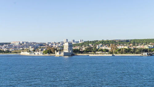 Scenic view of river by town against clear blue sky