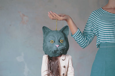 Midsection of young woman standing by girl wearing cat mask