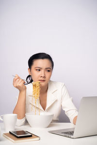 Young woman using phone while sitting on table